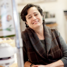 Marleny Franco, who has short brown hair and is wearing a sweater, poses leaning against a counter.