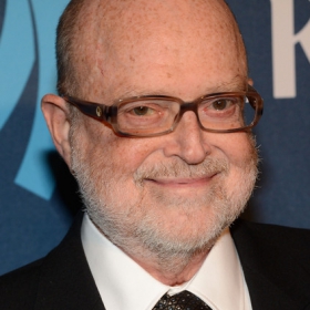 Arnie Kantrowitz, a white man wearing a suit and black rectangular glasses. 