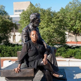 Noelle Williams, wearing all black, poses outdoors in front of a statue.