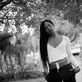 Black and white photo of Kiyan Williams in front of a tree