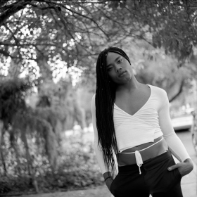 Black and white photo of Kiyan Williams in front of a tree 