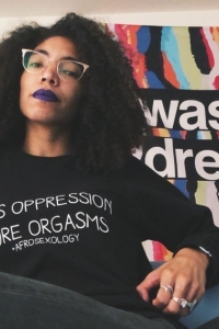 photo of Dominque Rocker in a sweatshirt that reads Less Oppression More Orgasms